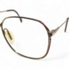 Close-up of Zeiss eyeglasses with 22kt gold finish, featuring red detailing and crystal accents.